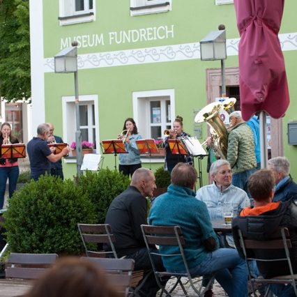 Musik und Begegnung auf dem Marktplatz in Thalmässing: Bläsergruppe und Gäste bei Kultur am Feierabend.